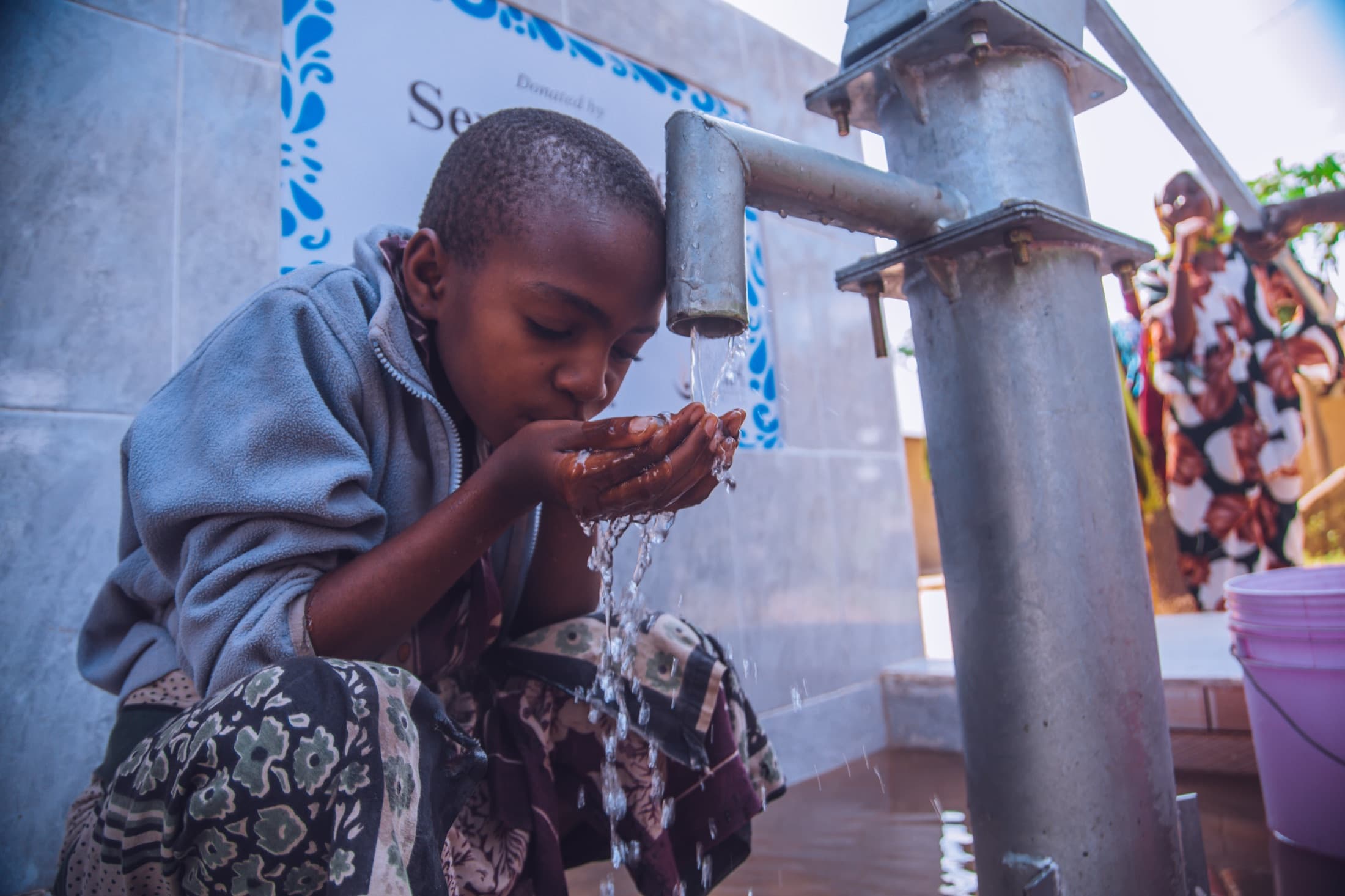 Girl collecting water at a completed community well