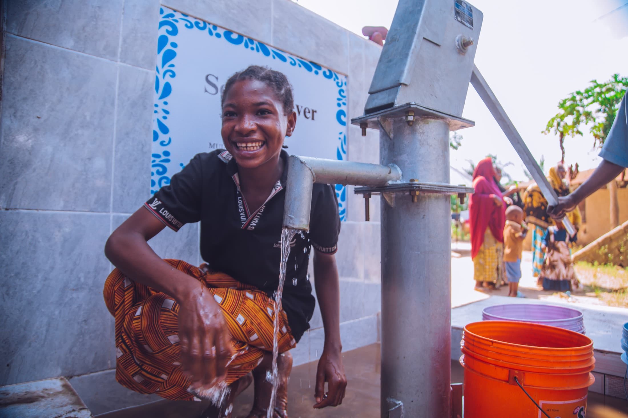 Community member collecting water from a completed well