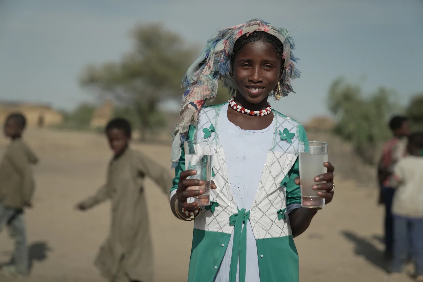 A girl holding clean water near her community