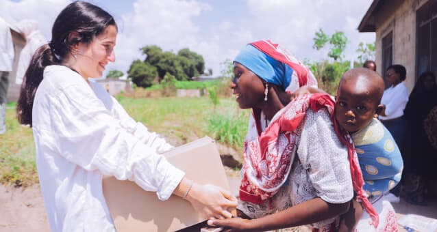 A relief volunteer delivering support to a mother and child
