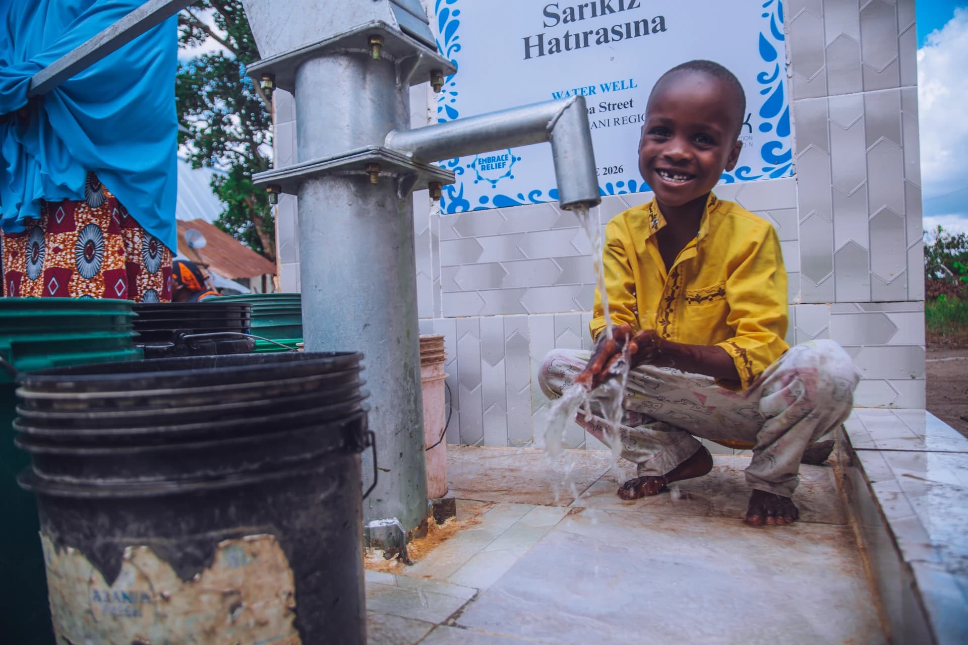 A smiling child washing his hands at an Embrace Relief water well
