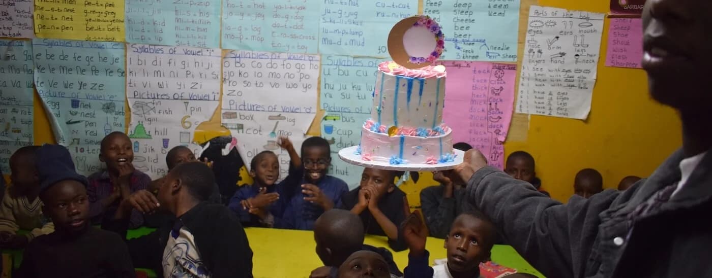 Children watching a birthday cake arrive during a classroom celebration